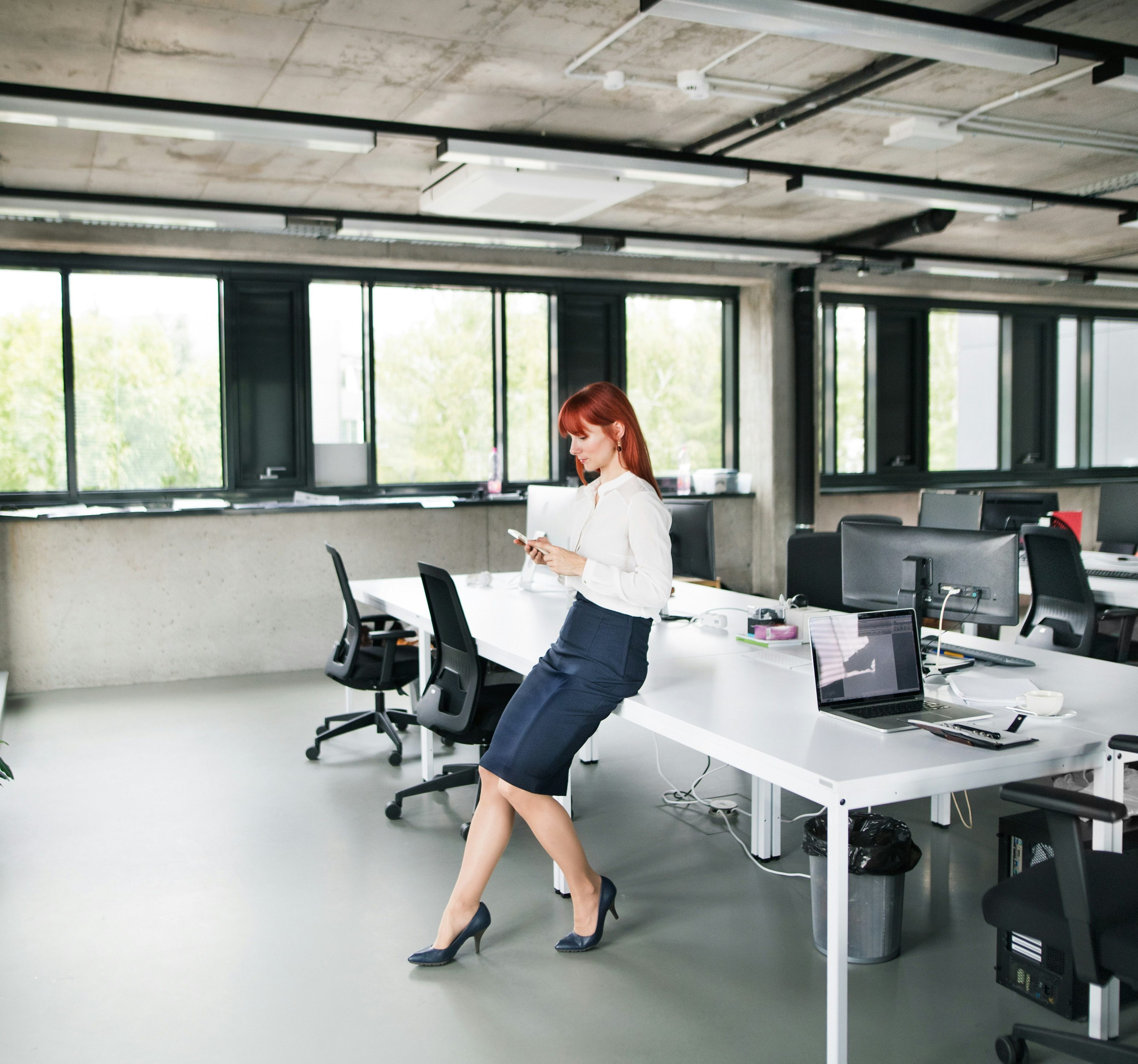 woman standing against desk on her phone in the office