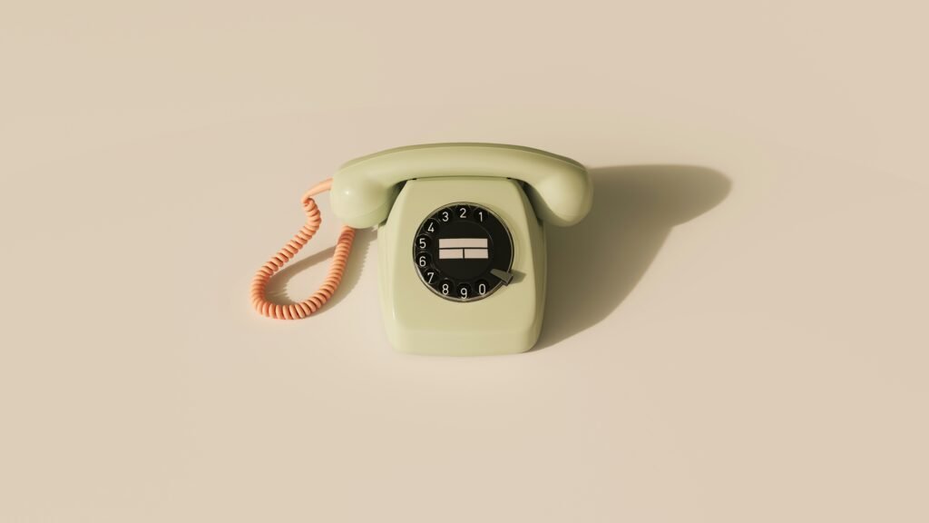 an old fasioned light green telephone with an orange cord